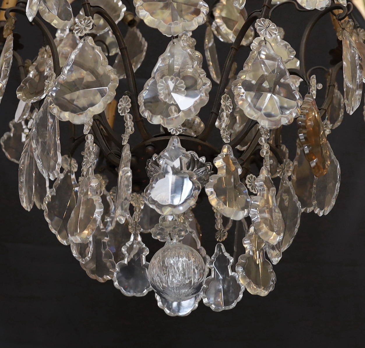 An early 20th century French bronze and cut glass six light chandelier, of particularly ornate design with spear finials, lozenge shaped drops and flower head motifs, height 101cm. width 60cm